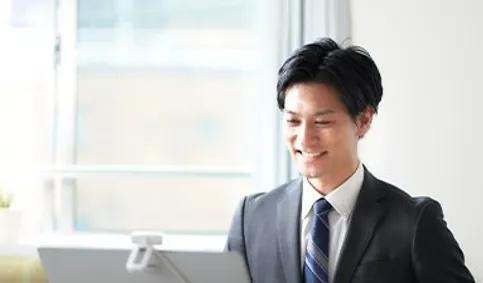 パソコンに向かい笑顔で対応するスーツ姿の男性