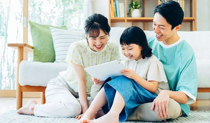 タブレットを見て笑う家族三人