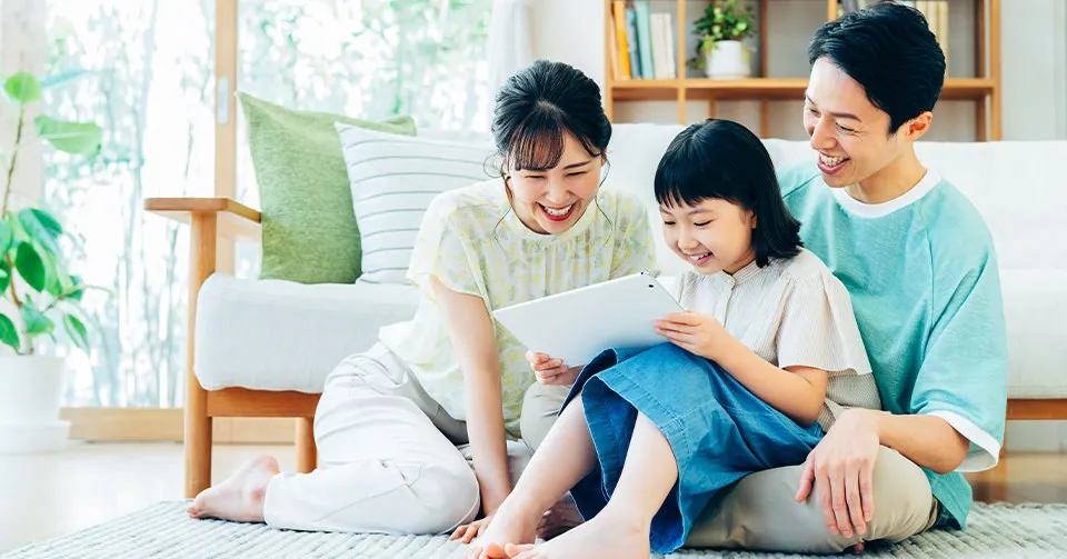 タブレットを見て笑う家族三人