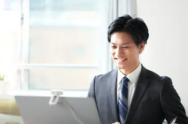 パソコンに向かい笑顔で対応するスーツ姿の男性